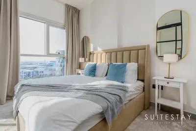 a bedroom with a bed with a mirror and a window at Chic Bright One Bedroom Suite in Dubai