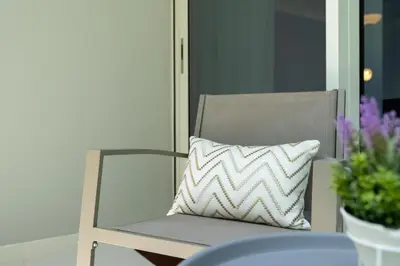 a white pillow sitting on a chair on a porch at White Sage- Damac Vera Residences 417 in Dubai