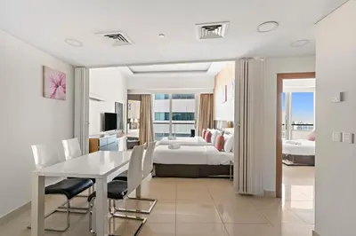 a hotel room with a bed and a table and chairs at Great 2BR APT Ocean Heights in Dubai