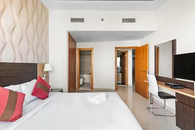 a bedroom with a bed and a desk and a television at Great 2BR APT Ocean Heights in Dubai