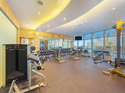 a gym with rows of tread machines and a large window at Great 2BR APT Ocean Heights in Dubai