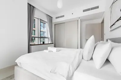 a white bedroom with a large white bed with pillows at StoneTree - Luxurious with Private Beach Access in Dubai