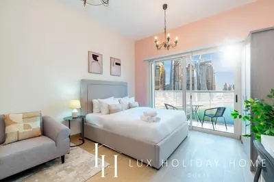 a bedroom with a bed and a couch and a window at LUX The Marina View Suite 1 in Dubai