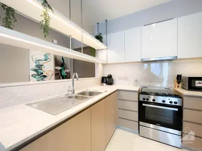a kitchen with white cabinets and a stove and sink at Luxury Burj Royale Apt Balcony Burj Khalifa View in Dubai