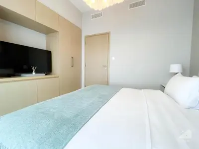 a bedroom with a large white bed with a flat screen tv at Burj Royale Luxury 1B Balcony & City View Downtown in Dubai