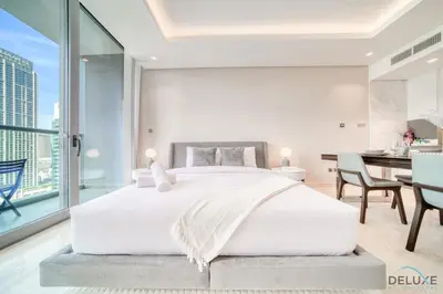a bedroom with a large white bed and a dining room at Plush Studio at The Sterling East House Business Bay by Deluxe Holiday Homes in Dubai
