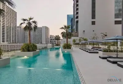 a large swimming pool with palm trees and buildings at Plush Studio at The Sterling East House Business Bay by Deluxe Holiday Homes in Dubai