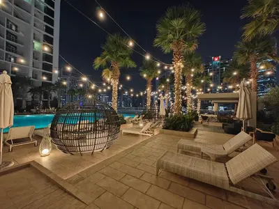 a hotel patio with palm trees and a pool at night at LeModCasa - Luxury smart Studio with Canal View Business Bay in Dubai