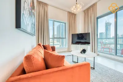 a living room with an orange couch and a tv at Keysplease Magnificent views of the Marina, Bay Central Dubai Marina in Dubai