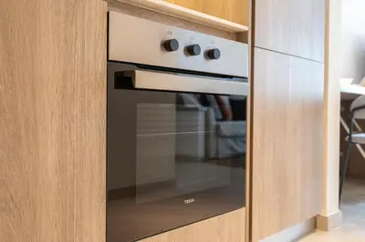 an oven in a wooden cabinet in a kitchen at Fashionable loft with catamaran net in JVC in Dubai