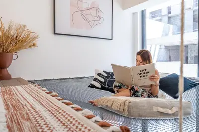 a woman laying on a bed reading a book at Fashionable loft with catamaran net in JVC in Dubai