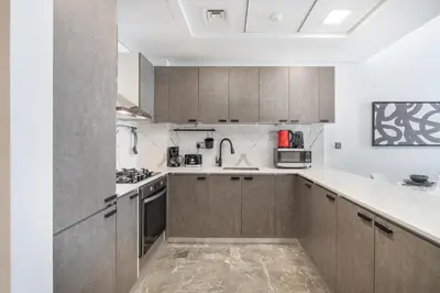 a kitchen with brown cabinets and white counter tops at Modern Comfort in a Spacious Apartment - Suiteable in Dubai