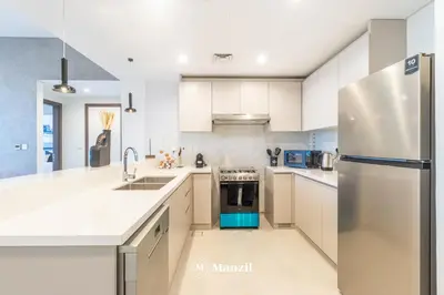 a kitchen with white cabinets and a stainless steel refrigerator at Manzil - 2BR Apt in Al Wasl Residences with Park View, Dubai Trade Center in Dubai