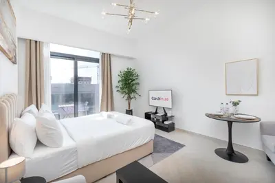 a white bedroom with a bed and a table at New Listing - TOP Amenities in JVC in Dubai