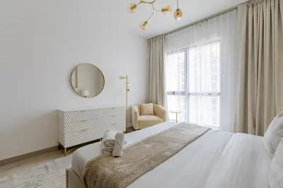 a white bedroom with a large bed and a chair at Nasma Luxury Stays - Fabulous Apartment With Balcony Near MJL's Souk in Dubai