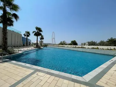 a large swimming pool with palm trees in the background at 1BR •The Address Beach Residence - High floor in Dubai