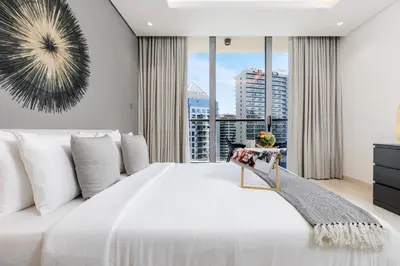 a bedroom with a large white bed and a large window at Maison Privee - Classy Urban Retreat with Amazing Dubai Canal Views in Dubai