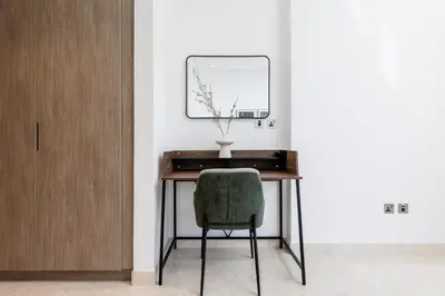 a desk with a green chair and a mirror at Maison Privee - Classy Urban Retreat with Amazing Dubai Canal Views in Dubai