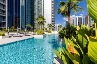 a swimming pool with palm trees and buildings at Maison Privee - Classy Urban Retreat with Amazing Dubai Canal Views in Dubai