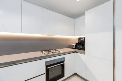 a kitchen with white cabinets and a stove at Maison Privee - Classy Urban Retreat with Amazing Dubai Canal Views in Dubai