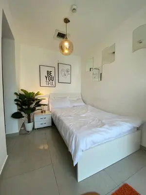 a white bedroom with a bed and a potted plant at Coliving Sharing Hostel ll in Dubai