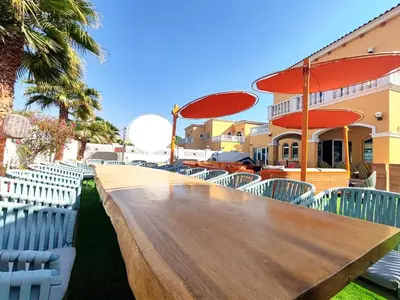 a long wooden table with chairs and umbrellas at Royal private pool, Lux 7-bedroom villa on Marina in Dubai