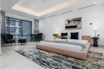 a bedroom with a large bed and a living room at Maison Privee - Exquisite Duplex with Private Patio & Loft Living in Dubai