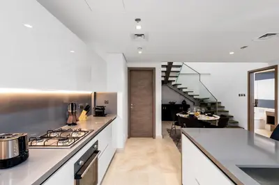 a kitchen with a stove and a dining room at Maison Privee - Exquisite Duplex with Private Patio & Loft Living in Dubai