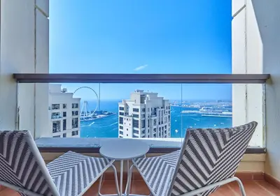 a balcony with chairs and a table and a large window at First Class Apartments in Heart of JBR, Steps to the Beach - 121 Living in Dubai