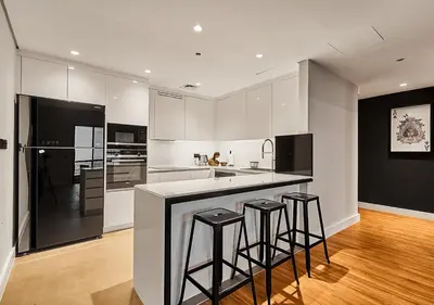 a kitchen with white cabinets and bar stools at First Class Apartments in Heart of JBR, Steps to the Beach - 121 Living in Dubai