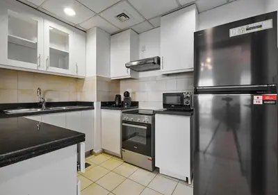 a kitchen with white cabinets and a stainless steel refrigerator at First Class Apartments in Heart of JBR, Steps to the Beach - 121 Living in Dubai