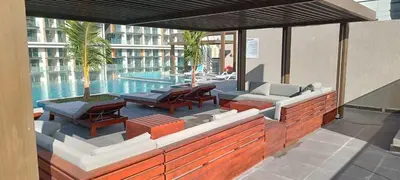 an outdoor patio with tables and chairs and a pool at Stylish Studio with Gym and Pool in Dubai