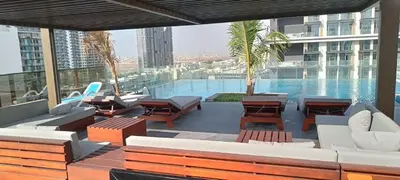 a patio with tables and chairs and a swimming pool at Stylish Studio with Gym and Pool in Dubai