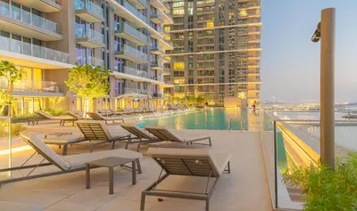a swimming pool with lounge chairs and a building at YOUR STAY APARTMENTS Luxury Beachfront Living in Dubai