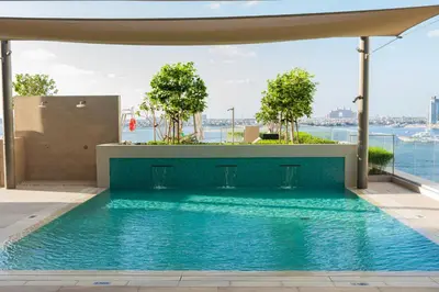 a swimming pool with a view of the water at YOUR STAY APARTMENTS Luxury Beachfront Living in Dubai