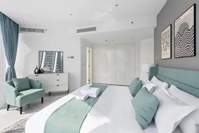 a bedroom with a large bed and a green chair at StoneTree - Panoramic View - Spacious 2BR in Dubai