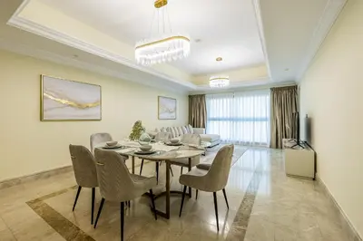 a dining room and living room with a table and chairs at Apartment in Fairmont South Residence Palm Jumeirah in Dubai