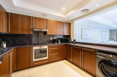 a kitchen with wooden cabinets and a dishwasher at Apartment in Fairmont South Residence Palm Jumeirah in Dubai