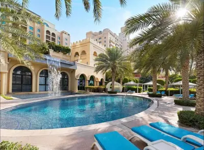 a pool at the resort with lounge chairs and palm trees at Apartment in Fairmont South Residence Palm Jumeirah in Dubai