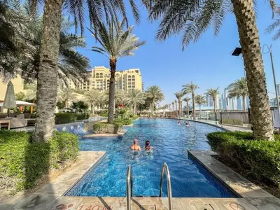 a pool at the resort with palm trees at Apartment in Fairmont South Residence Palm Jumeirah in Dubai
