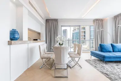 a living room with a blue couch and a table with chairs at The Residences Towers - 3 Minute Walk to Dubai Fountain in Dubai