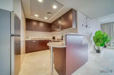 a kitchen with wooden cabinets and a counter top at Amazing 2BR at Sky Gardens DIFC by Deluxe Holiday Homes in Dubai