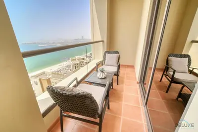 a balcony with chairs and a table and a view of the ocean at Urbane 2BR At Shams 1 JBR by Deluxe Holiday Homes in Dubai