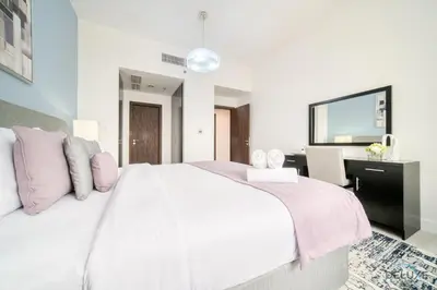 a bedroom with a large white bed and a desk at Urbane 2BR At Shams 1 JBR by Deluxe Holiday Homes in Dubai