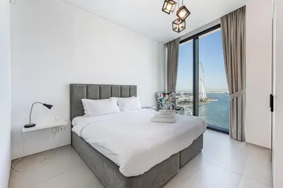 a bedroom with a large bed with a large window at Manzil - 2BR Apartment in The Address JBR with Private Beach Access & Dubai Eye View in Dubai