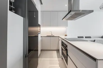 a white kitchen with a sink and a counter at Manzil - 2BR Apartment in The Address JBR with Private Beach Access & Dubai Eye View in Dubai