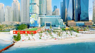 a beach with chairs and umbrellas in front of a city at FIVE LUXE in Dubai