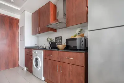 a kitchen with wooden cabinets and a washer and dryer at Frank Porter - Lake View Tower in Dubai