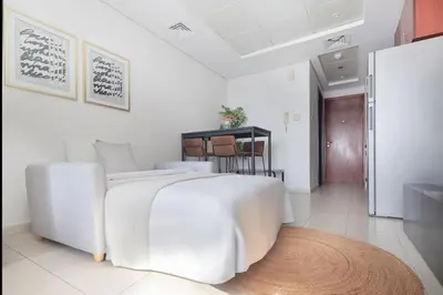 a white bedroom with a white bed and a rug at Frank Porter - Lake View Tower in Dubai