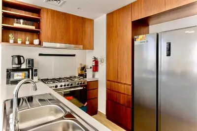 a kitchen with a stainless steel refrigerator and wooden cabinets at Ocean Majestic Full Sea View at Le Pont in Dubai